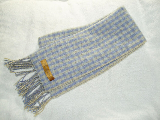 Folded pale blue and cream checked woollen scarf with knotted fringe on a white surface
