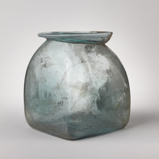 Pale blue-green square glass jar with a wide flat lid, shot on a plain light grey studio background