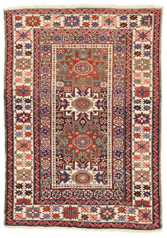Hand-knotted wool rug with red, blue and cream geometric medallions and fringed ends, laid flat on white
